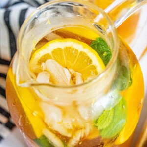 lemonade iced tea arnold palmer in a pitcher with sliced citrus and mint