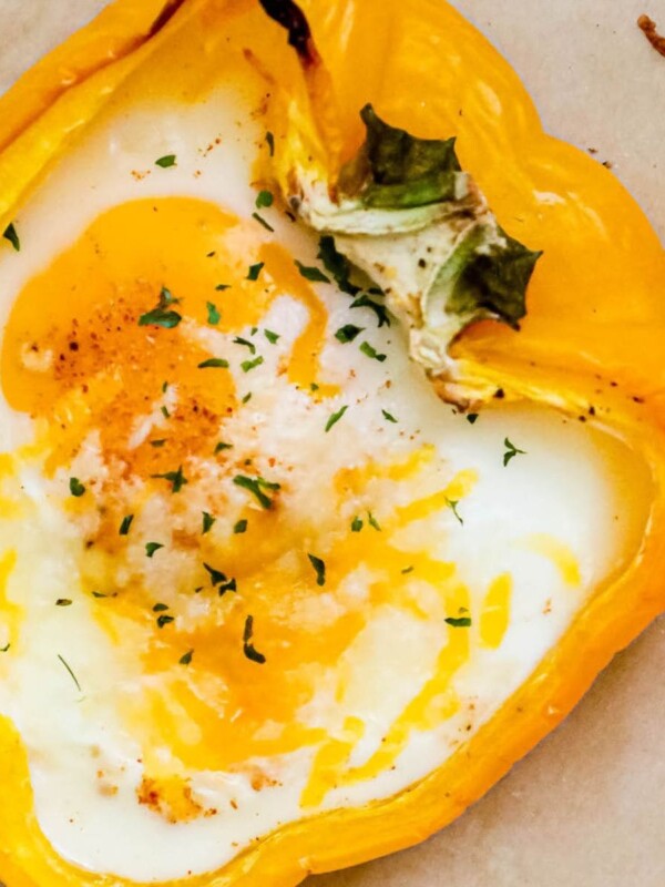 baked eggs inside halves of bell peppers with melted cheese and herbs on top