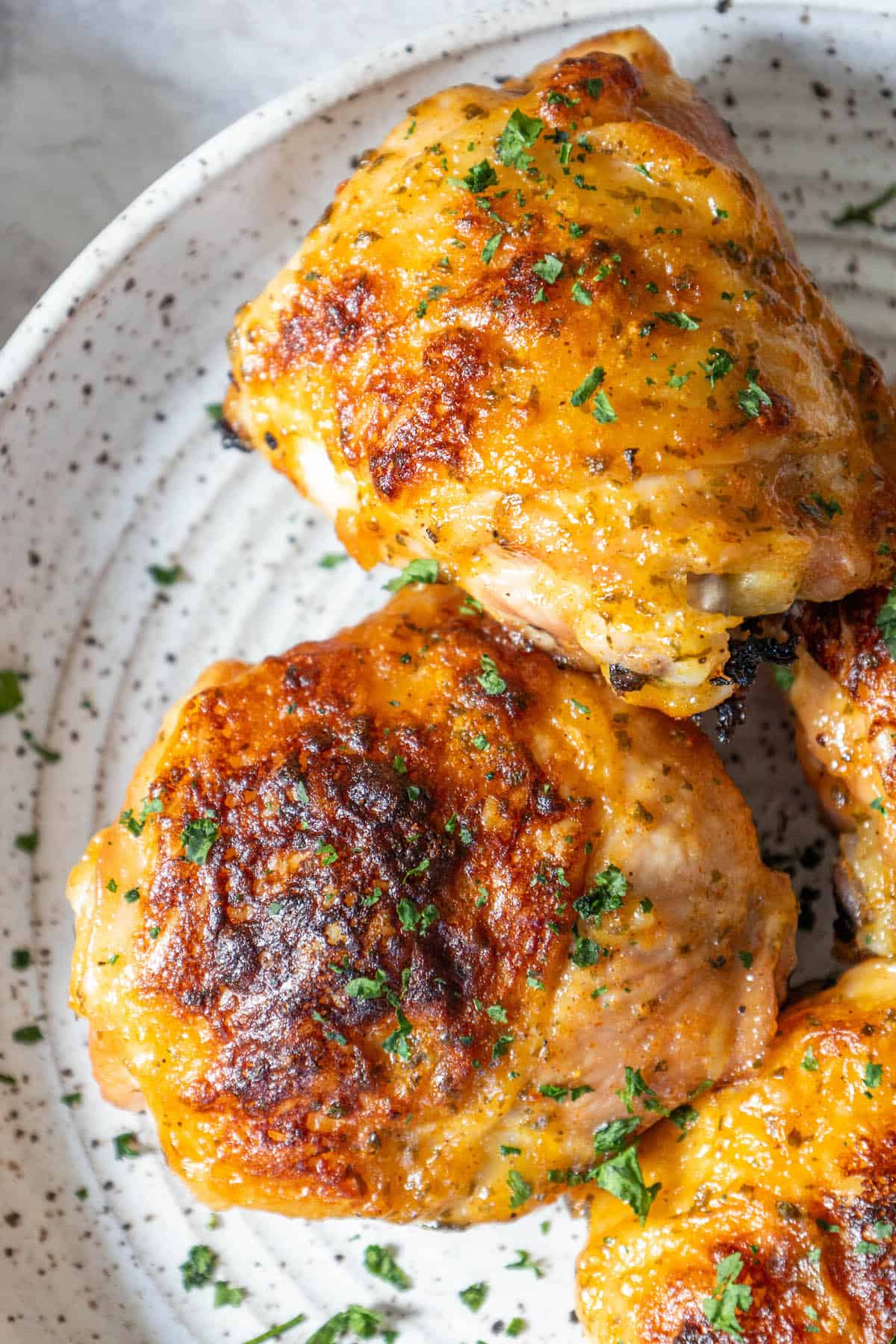 Chicken breasts on a white plate with herbs and baked ranch chicken thighs.