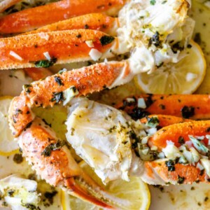 Baked Snow Crab Legs with lemon and herbs on a plate.