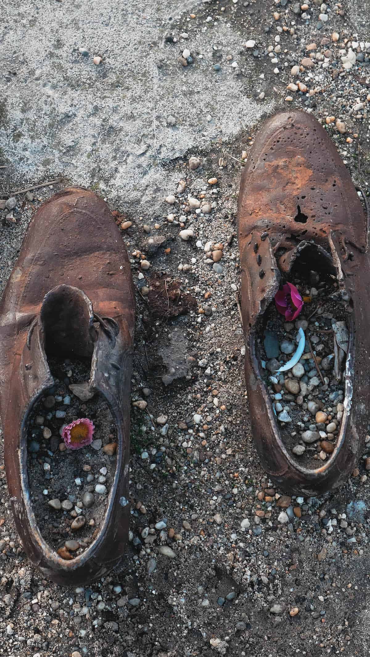 A pair of rusty shoes on the ground, next to a hearty bowl of Easy One Pot Authentic Hungarian Goulash Beef Stew.