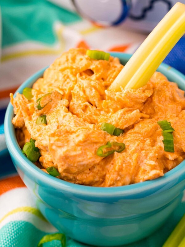 Buffalo chicken dip served in a blue bowl alongside celery sticks.