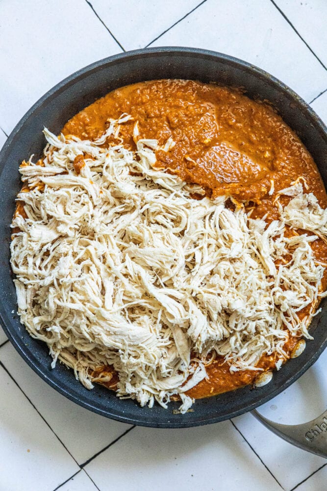 tinga sauce in a pan with shredded chicken poured on top 