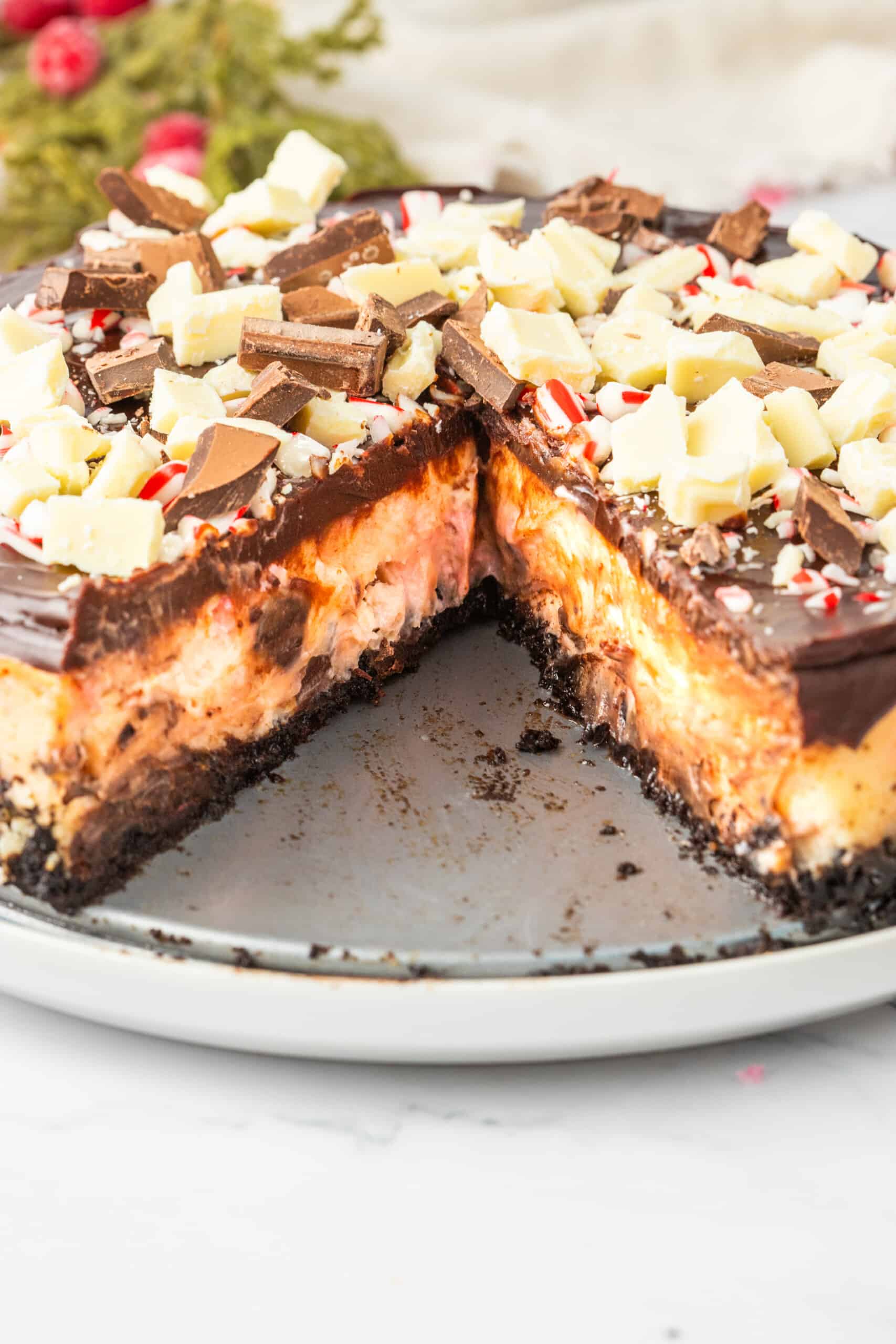 A chocolate peppermint cheesecake with a slice taken out.