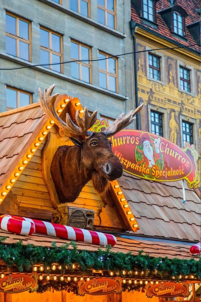 A Wroclaw Christmas market featuring a unique deer head decoration on the roof.