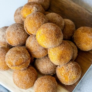 picture of donut holes rubbed in cinnamon sugar stacked on a cutting board