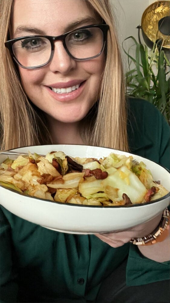 A woman in glasses holding a plate of food showcasing Courtney O'Dell Sweet C's Designs Recipes.