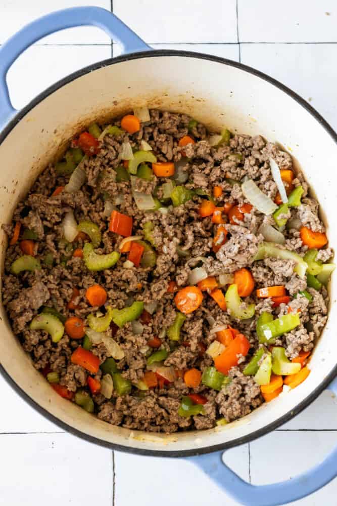 Easy One Pot Cheeseburger Soup Recipe with ground beef and vegetables cooked in a blue pot.