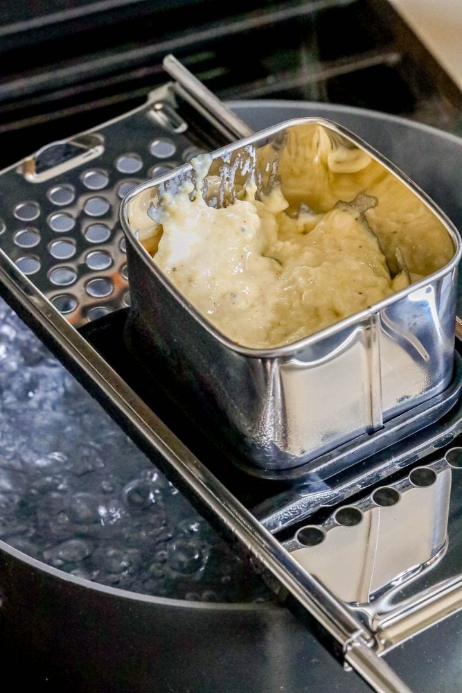 spaetzle in a spaetzle maker over a pot of boiling water