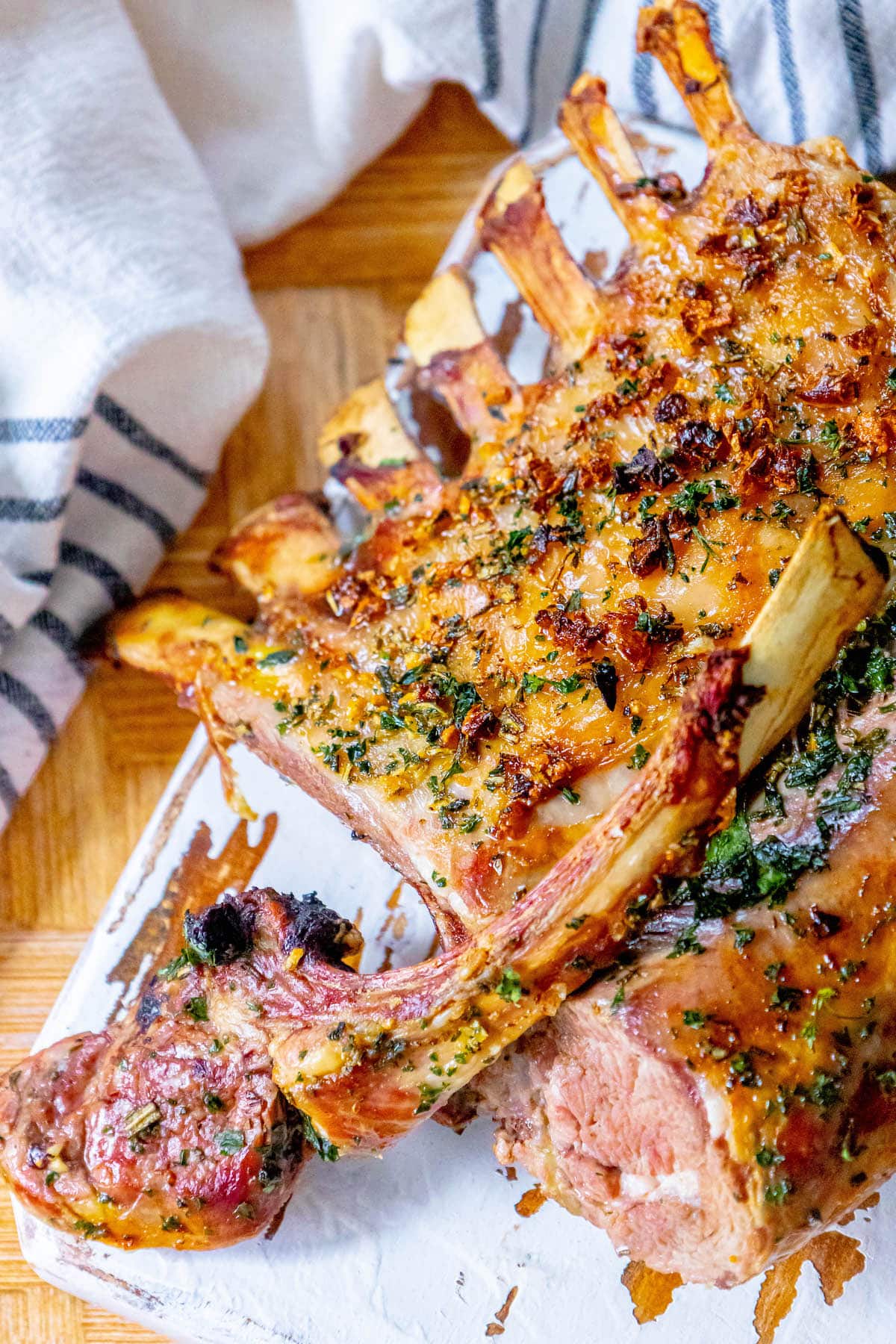 roasted rack of lamb with garlic and herb crust on a white speckled plate on a table