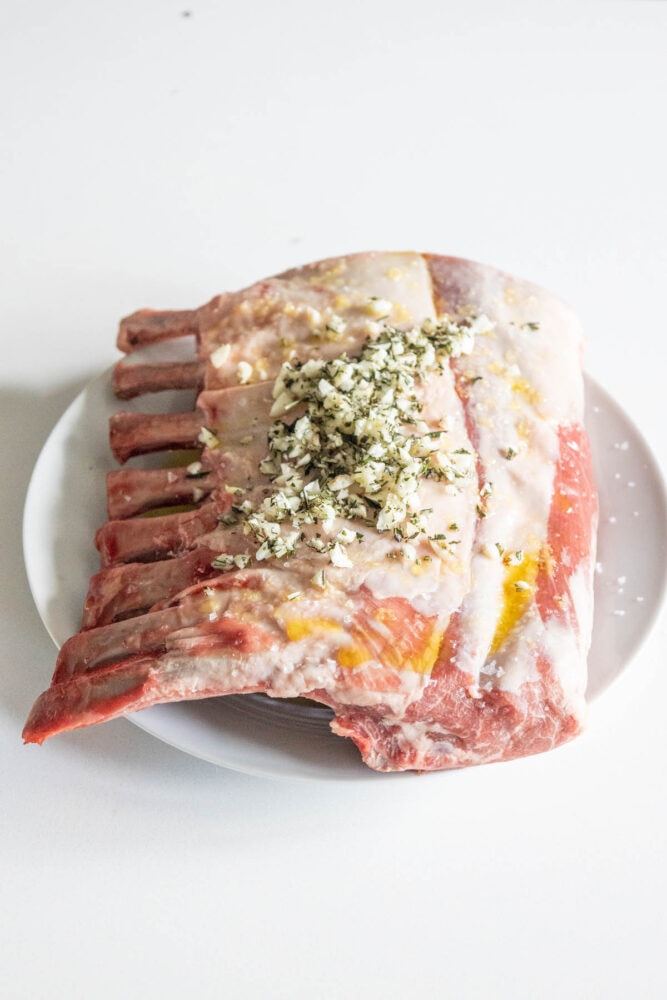 rack of lamb covered in olive oil, minced garlic, and diced herbs