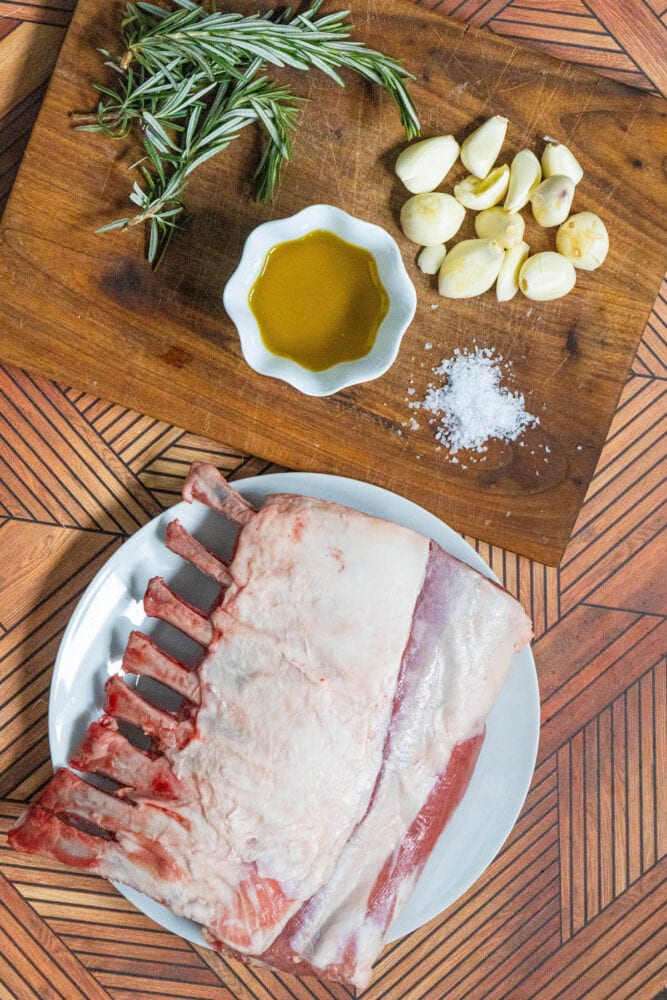 frenched rack of lamb, olive oil, salt, garlic, herbs on a table