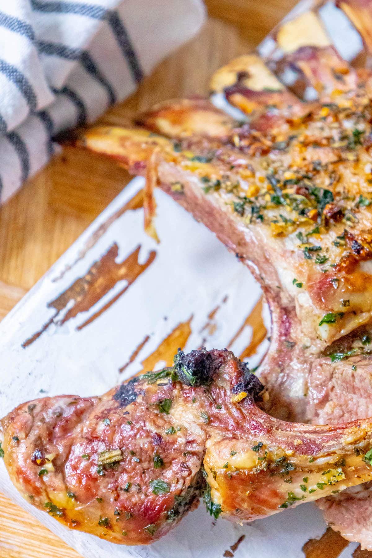 roasted rack of lamb with garlic and herb crust on a white speckled plate on a table