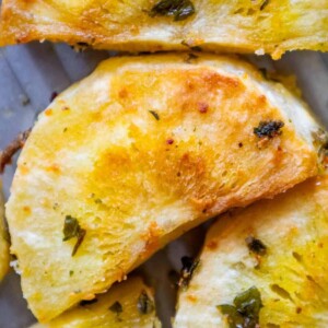 A herbed slice of pineapple with parsley on a plate.