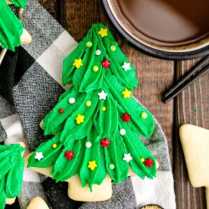 picture of iced christmas tree cookie on a table next to a cup of coffee