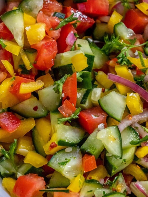 chopped bell pepper, cucumber, cherry tomatoes, red onion, and parsley in a white bowl