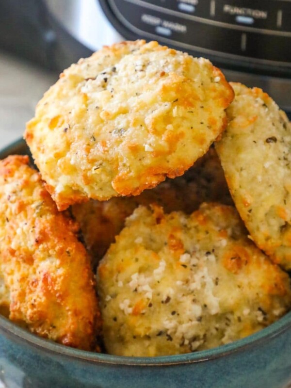 a bowl of rolls stacked in a blue bowl in front of an air fryer machine