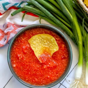 picture of a chip in a bowl of salsa on a table