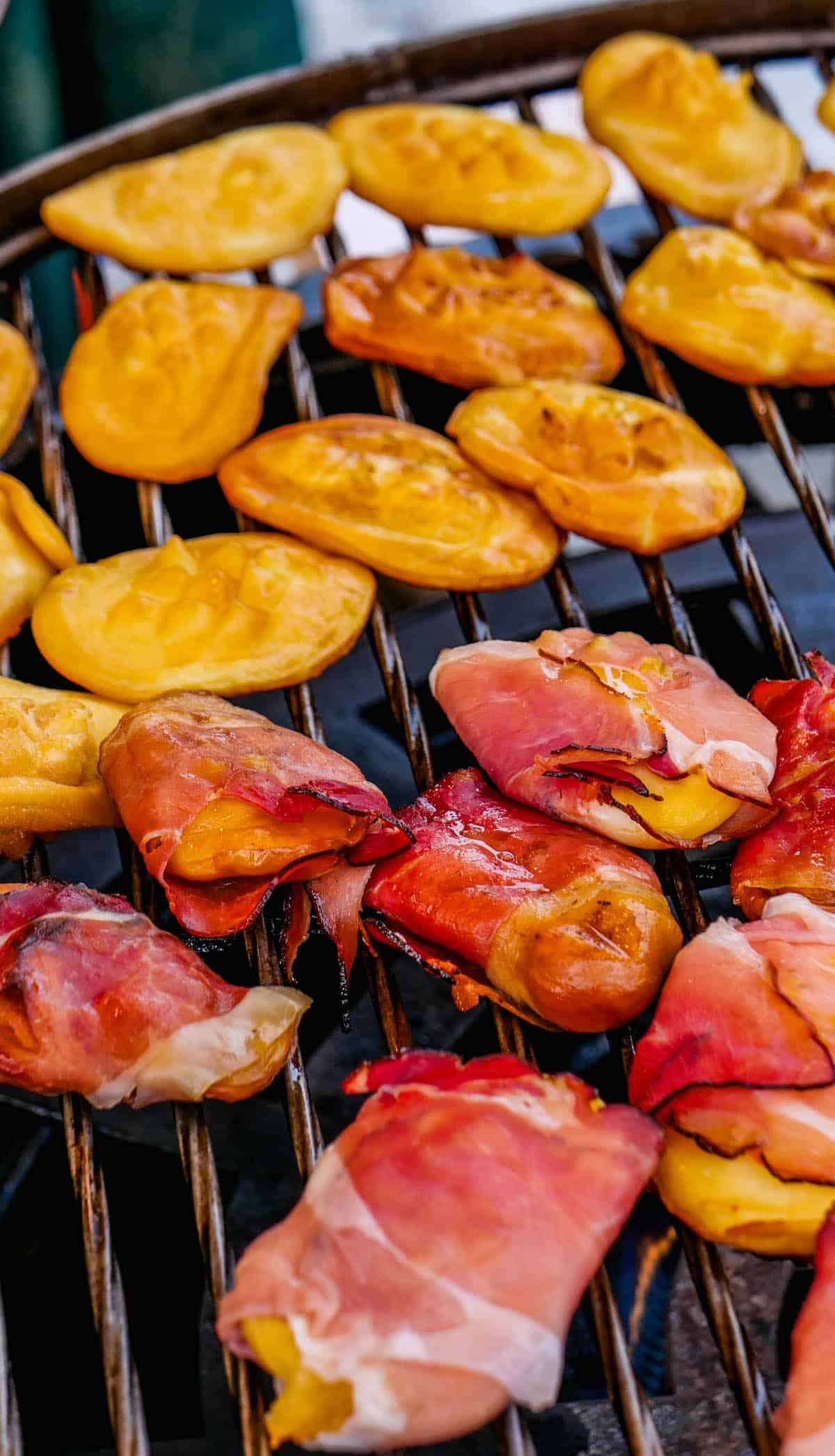 On the barbecue, enticing aromas fill the air with grilled delicacies like yellow empanadas and prosciutto-wrapped treats, reminiscent of the festive flavors you'd find at a Krakow Christmas Market.