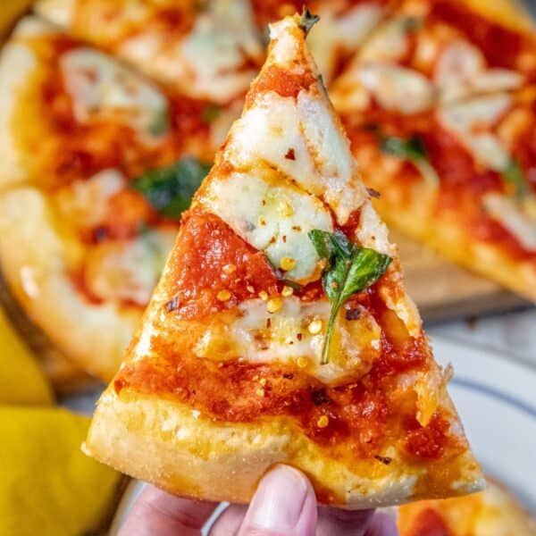 A person proudly displaying a classic margherita pizza.