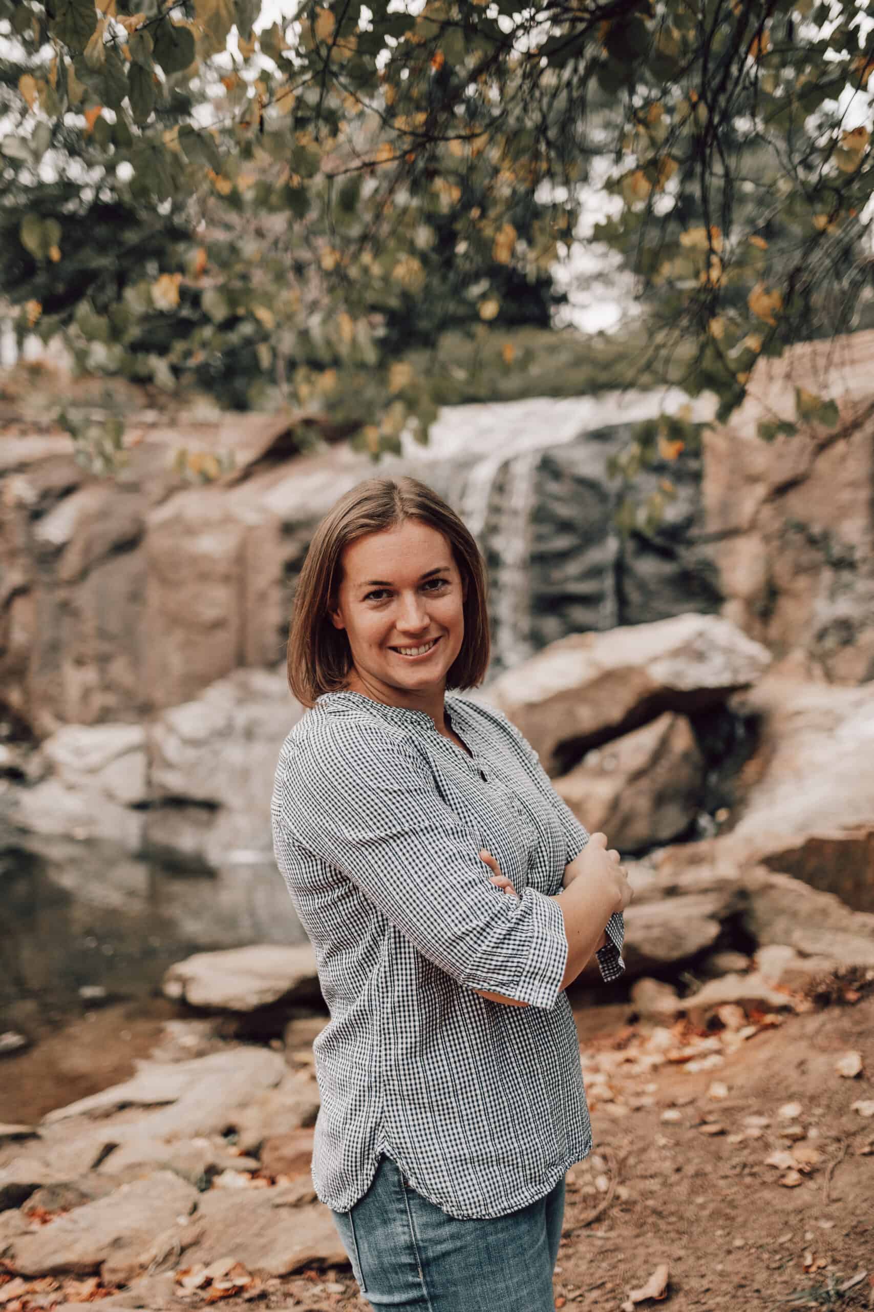 A woman being amazed by the breathtaking view of a waterfall in front, captured by Sweet C's Designs Blog.