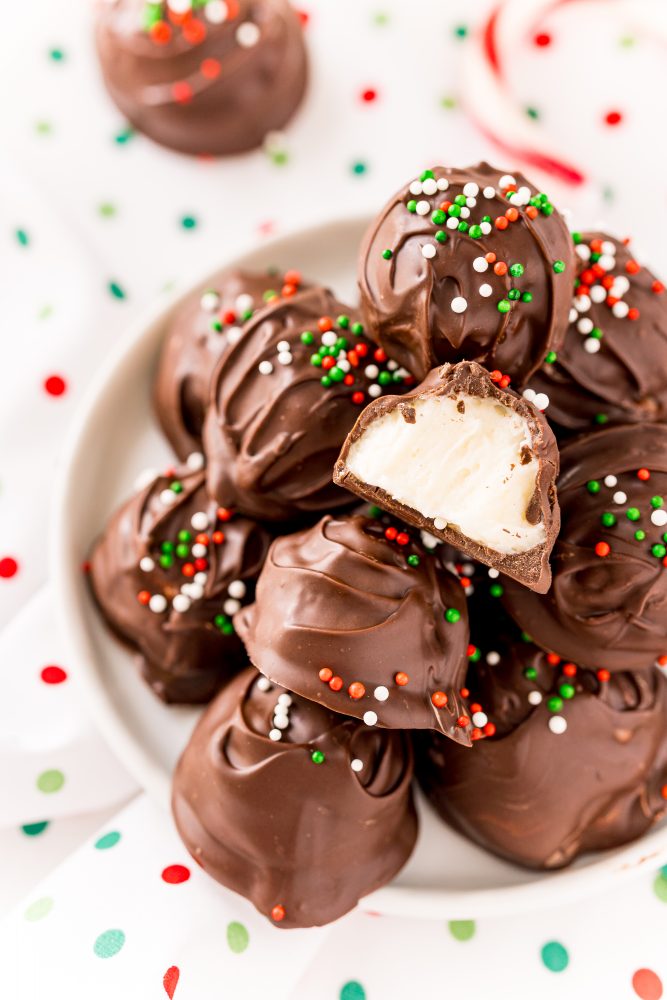 a pile of chocolate buttercream candies with green, white, and red sprinkles on a white plate