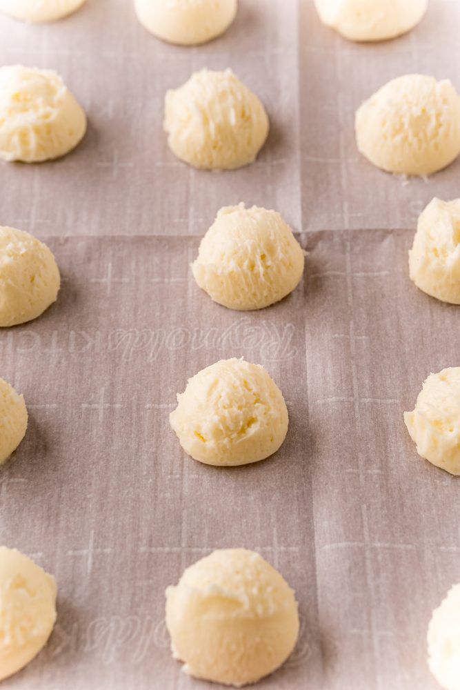 small balls of creamed butter, sugar, and cream cheese on a baking sheet lined with parchment paper