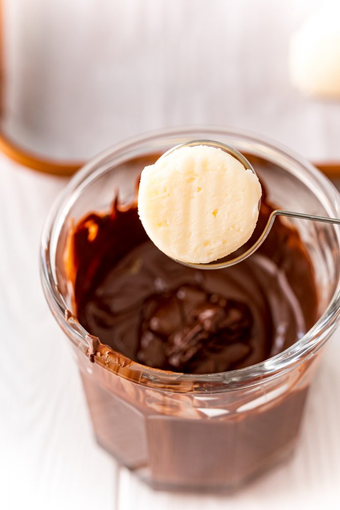 a buttercream ball on a dipping fork over a bowl of melted chocolate