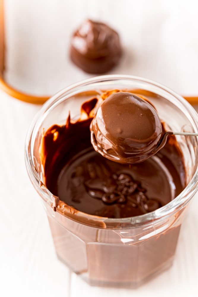 buttercream candy ball on a dipping fork covered in melted chocolate