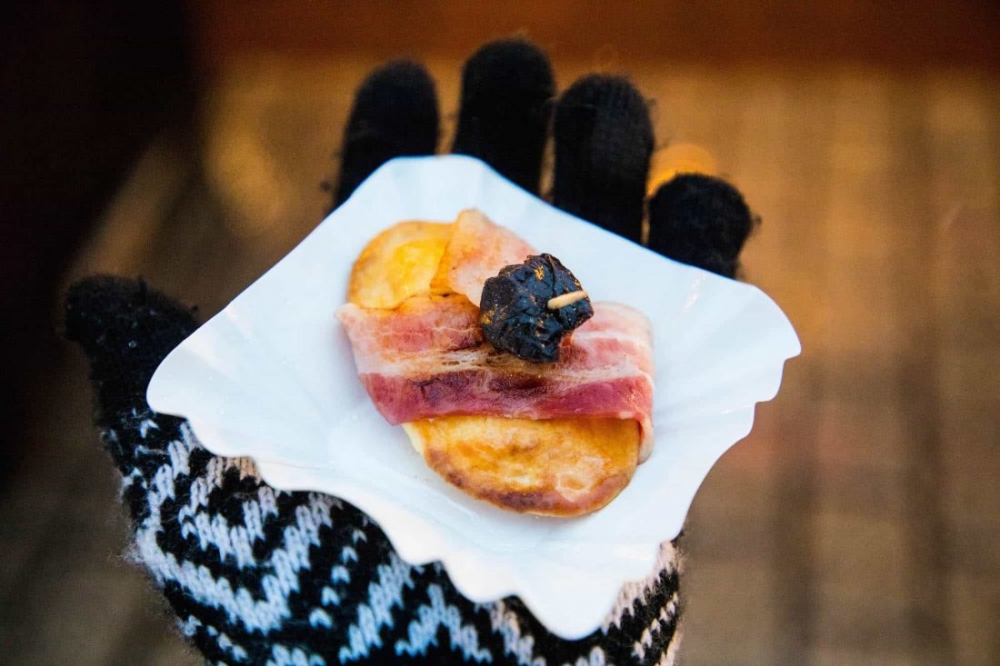 A hand presents a small plate of food at the Krakow Christmas Market.