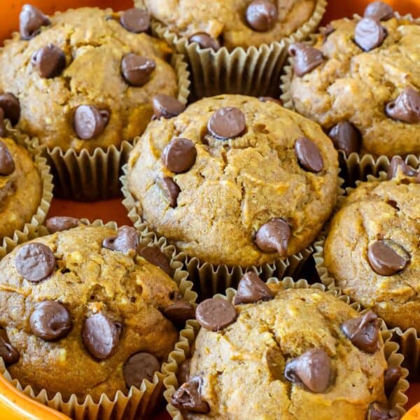 Muffins topped with chocolate chips arranged in a pile on a tray.