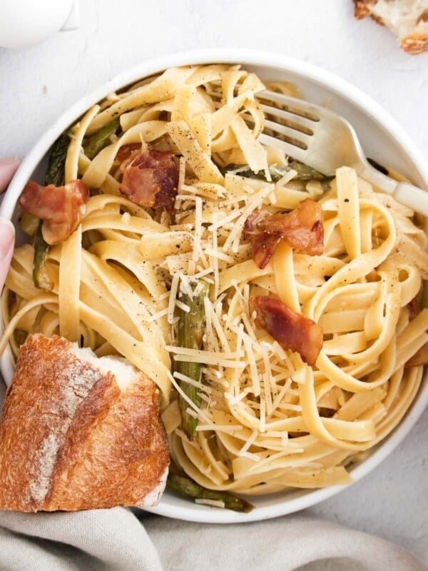 picture of hand holding bowl of asparagus carbonara pasta