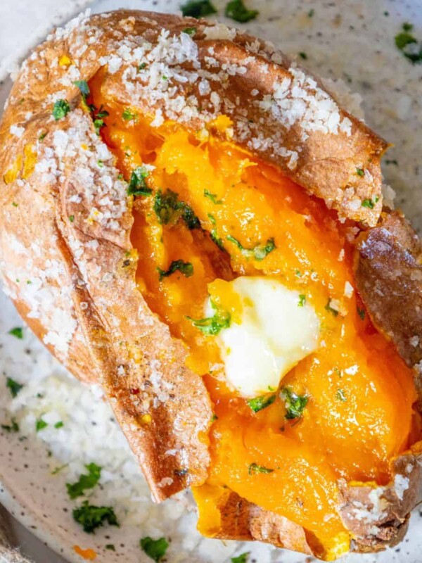 A salt-baked sweet potato with butter and parsley on a plate.