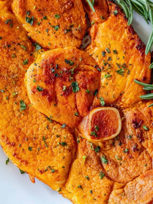 Skillet ham steak served with roasted sweet potatoes and rosemary sprigs.