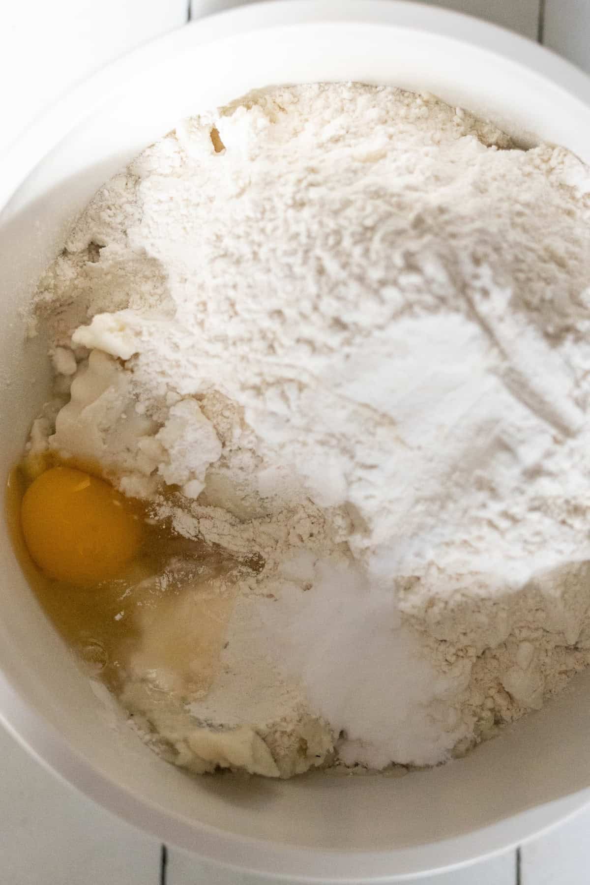 A mixing bowl containing flour, an egg, and other baking ingredients is ready to create delicious Scottish tattie scones.