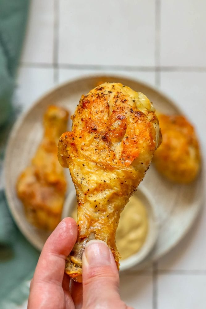 picture of a hand holding an air fried chicken drumstick 