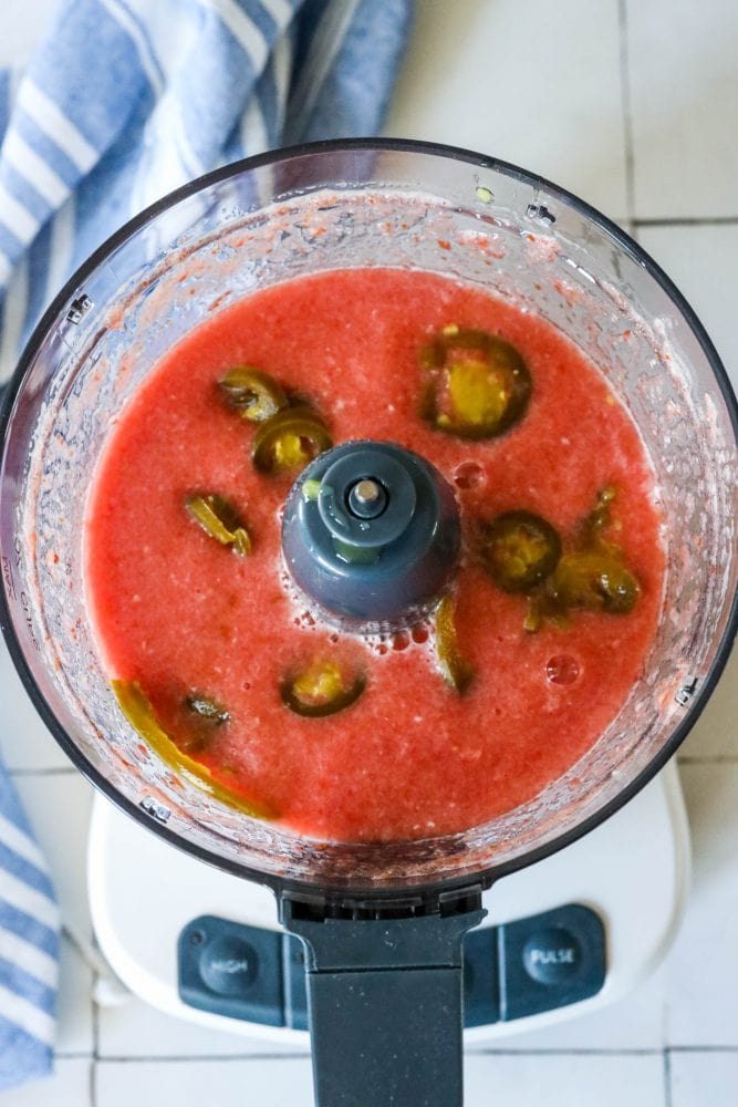 picture of blended tomatoes and onions in a food processor with jalapenos