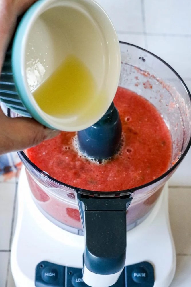 picture of hand adding lime juice to food processor with salsa in it