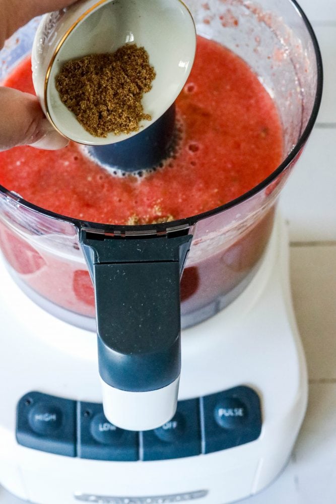 picture of hand adding coriander to food processor with salsa in it