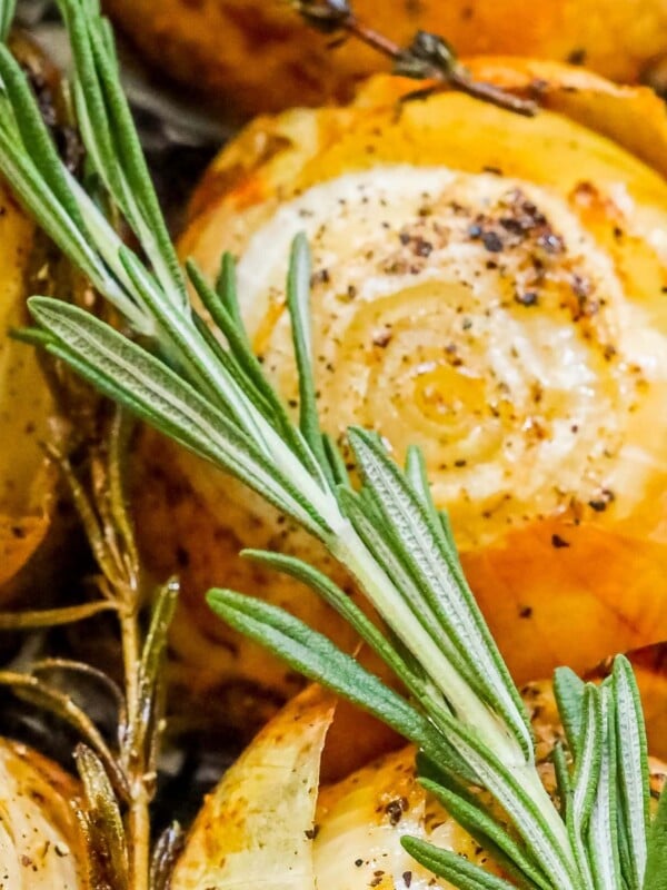 picture of whole roasted onions in a tray with pepper and rosemary