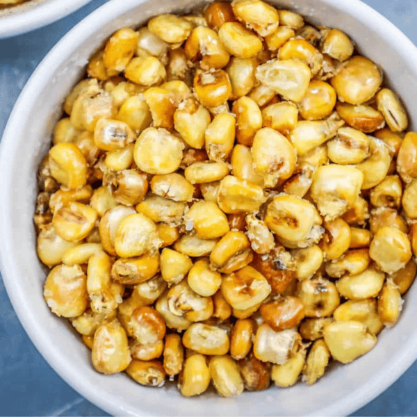 Close-up of a bowl filled with homemade corn nuts, featuring golden yellow and lightly browned baked corn kernels.